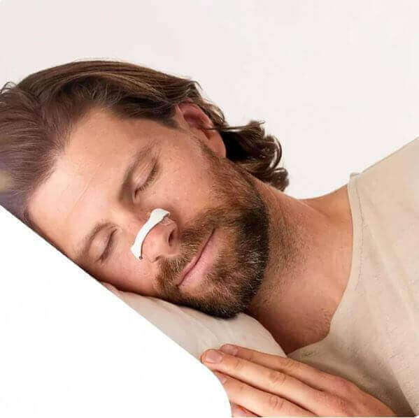 Man sleeping peacefully with a magnetic nose strip to alleviate snoring.